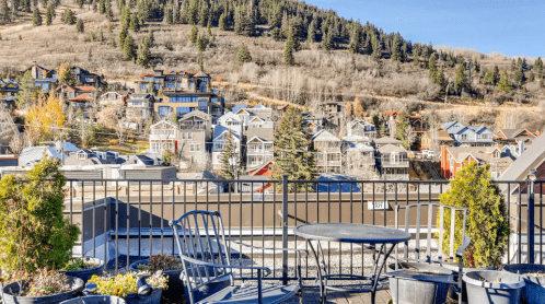 A scenic view from a rooftop terrace overlooking a hillside neighborhood with houses and trees.